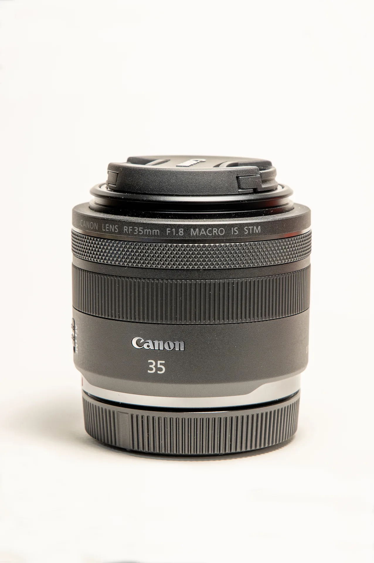 Canon RF 35mm F1.8 Macro IS STM lens standing on a white background