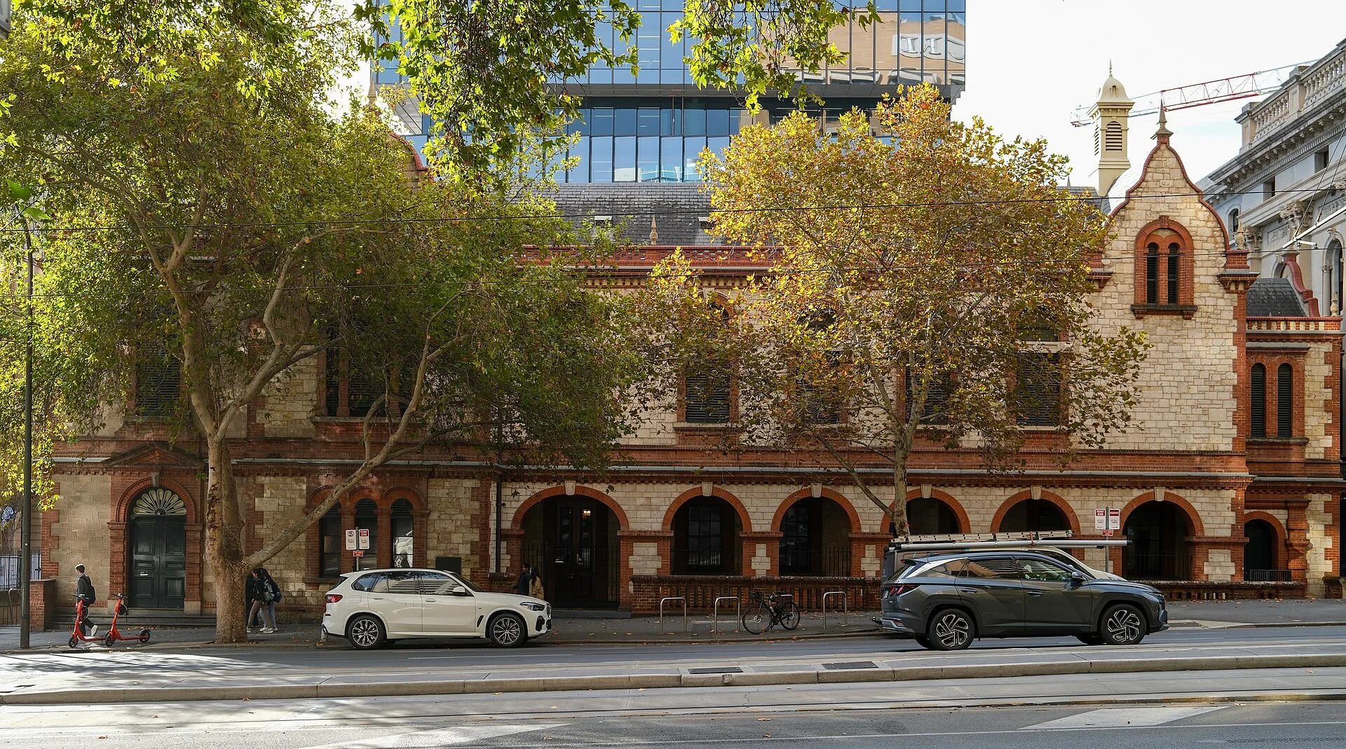 The red-brick and stone Old Parliament House in Adelaide behind autumn trees
