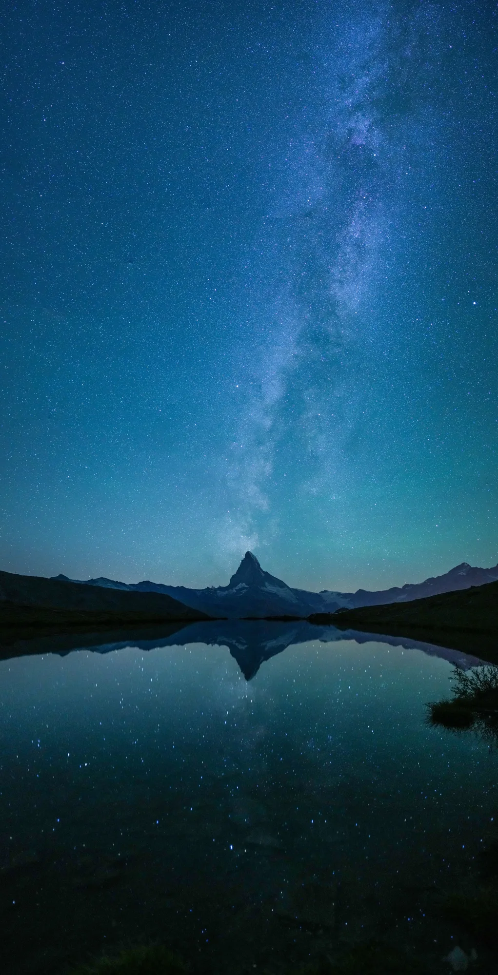The Milky Way rising over the Matterhorn, reflected in a still mountain lake at night