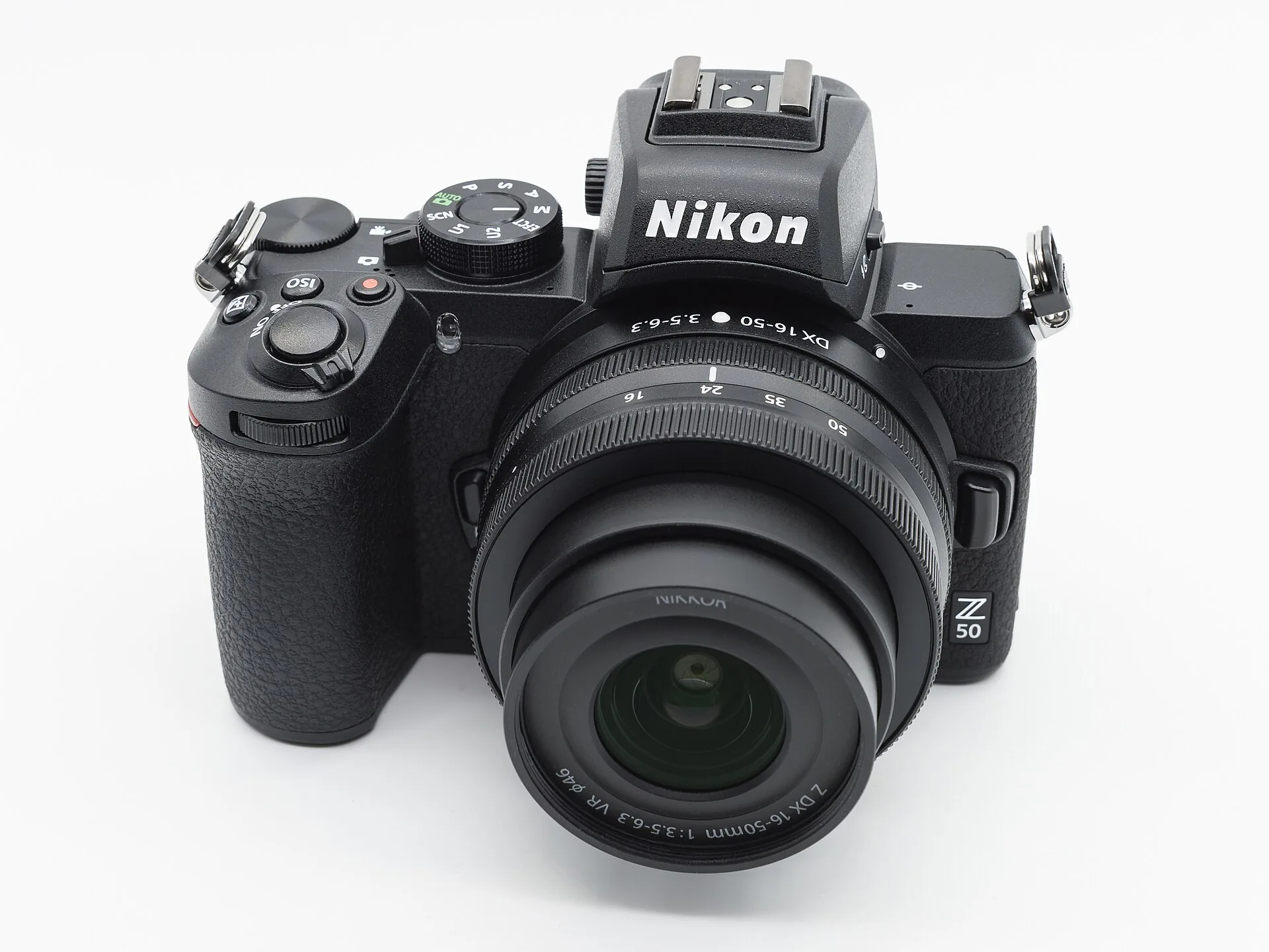 A black Nikon Z50 with a compact NIKKOR Z DX kit zoom lens, seen from the front on a white background