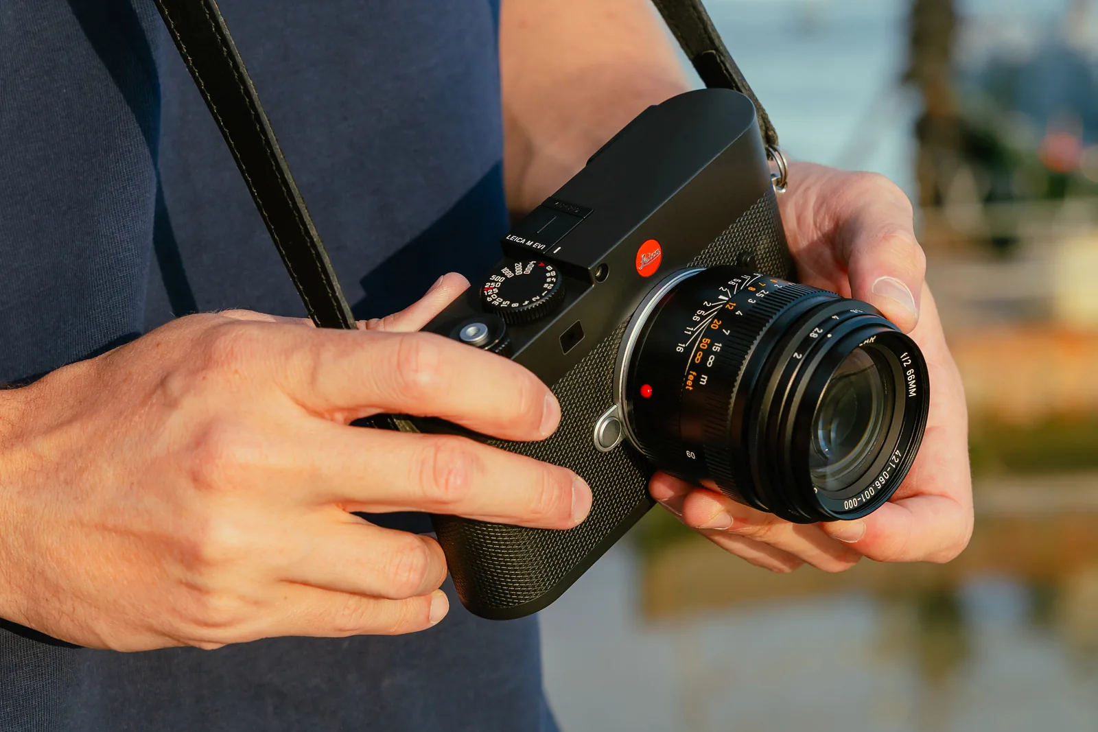 Summicron-M 66mm f/2 on a black Leica M camera, held in two hands